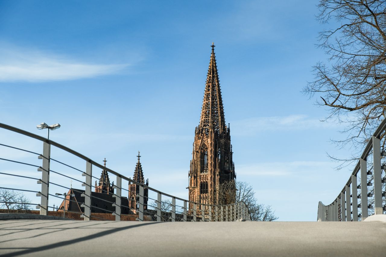 menu-01 View of the iconic Münster Cathedral Tower from a bridge on a clear spring day.
